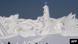 Tourists walk in front of an ice sculpture ahead of the opening of the Harbin International Snow and Sculpture Festival in Harbin, in China&#39;s northeast Heilongjiang province, Jan. 4, 2020.