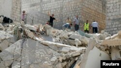 A man gestures as residents look for survivors under the rubble of collapsed buildings after what activists said was a vacuum bomb was dropped by forces of Syria's President Bashar al-Assad on Maarat Al-Nouman, south of Idlib September 18, 2014.