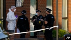 Police officers talk to a forensic technician at the scene outside the Belfairs Methodist Church, where British lawmaker David Amess died after being stabbed at a meeting with constituents, in Leigh-on-Sea, Essex, England, Oct. 15, 2021.