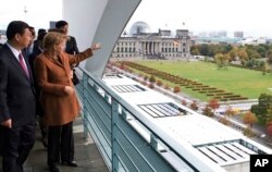 2009年10月12日，德国总理默克尔在总理府把德国议会大楼指给中国副主席习近平看