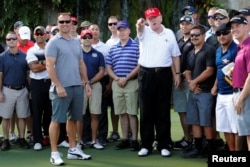 U.S. President Donald Trump stands with U.S. Coast Guard Chief Warrant Officer Gene Gibson, left, commanding officer of the Lake Worth Inlet Station, as Trump plays host to members of the U.S. Coast Guard he invited to play golf at his Trump International Golf Club in West Palm Beach, Fla., Dec. 29, 2017.