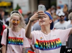 A participant takes pictures during a gay pride parade in Bucharest, Romania, June 9, 2018. People taking part in the parade demanded more rights and acceptance for same-sex couples.