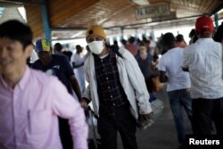 Seorang pelancong bermasker keluar dari Bandara Internasional Toussaint Louverture, di Port-au-Prince, Haiti 15 Maret 2020. (Foto: Reuters)