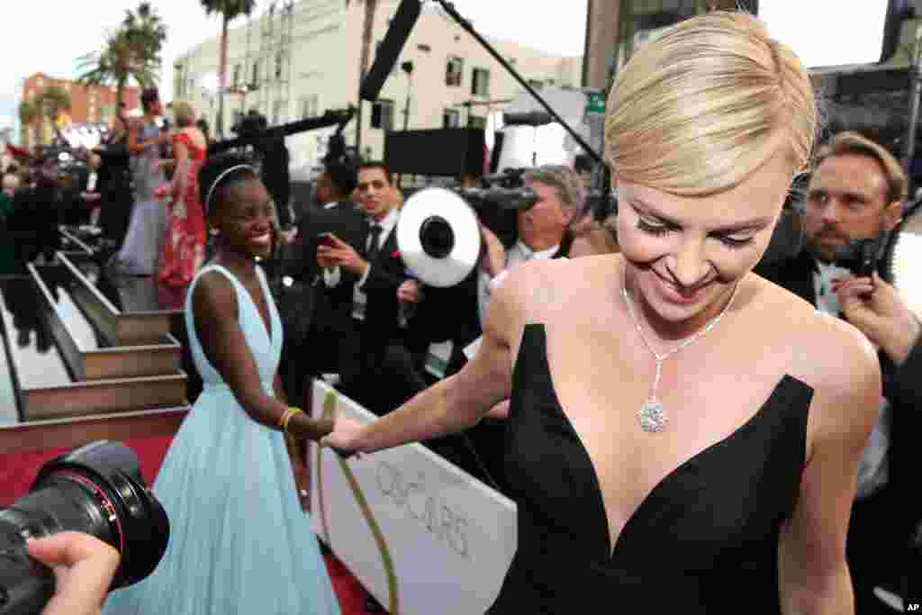 Lupita Nyong'o, left, and Charlize Theron arrive at the Oscars on March 2, 2014, at the Dolby Theatre in Los Angeles. 