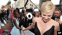 Lupita Nyong'o, izq., y Charlize Theron a su llegada a la entrega de premios Oscar en el Teatro Dolby de Los Angeles, California. 2-3-14. Theron protagoniza "Tully", que se estrena esta semana en EE.UU.