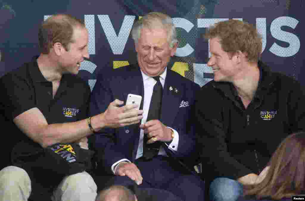 Britain's Princes William (L), Charles (C) and Harry look at a mobile phone during the Invictus Games in the Lee Valley Athletics Centre in north London, England.