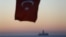 FILE - The Turkish national flag hangs in the foreground as drilling vessel Fatih is seen off the Mediterranean resort city of Antalya, Turkey.