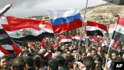 Supporters of Syria's President Bashar al-Assad hold up national flags and a Russian flag as they attend a rally at Umayyad square in Damascus, Syria, March 15, 2012.