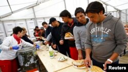 Para migran mengambil makanan di tempat penampungan di gedung olahraga Hanau, Jerman. (Foto: Dok)