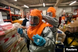 FILE - Volunteers who will be sent to Africa are taught how to work with patients infected with the Ebola virus during a training session at AP-HP hospital Henri Mondor in Creteil, a suburb of Paris, Oct. 22, 2014.