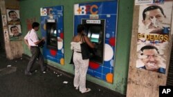 Warga Venezuela menarik uang tunai dari mesin ATM di Caracas, Venezuela (8/2). Pemerintah Venezuela mengumumkan devaluasi (penurunan nilai) mata uang bolivar terhadap dolar menjadi enam koma 30 bolivar untuk satu dolar, yang mulai berlaku hari Rabu pekan mendatang. 