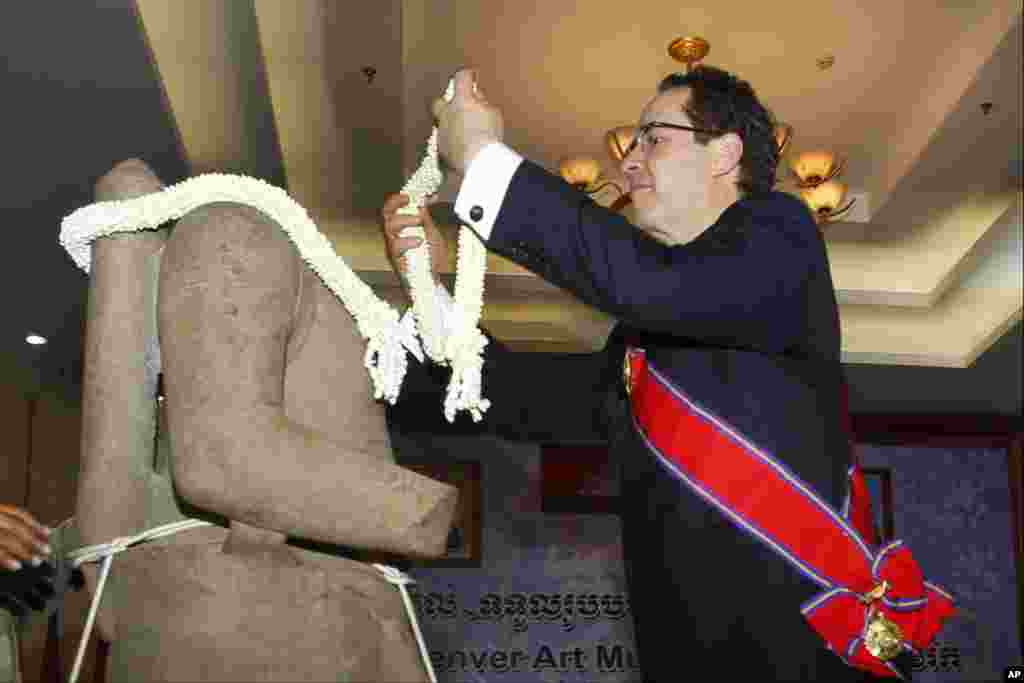 Denver Art Museum Director Christoph Heinrich decorates a bundle of jasmine to the Torso of Rama, a 10th century stone statue, during a handing over ceremony in Phnom Penh, Cambodia.