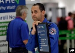 A Transportation Security Administration employee works at a security checkpoint at Miami International Airport, Jan. 18, 2019, in Miami.
