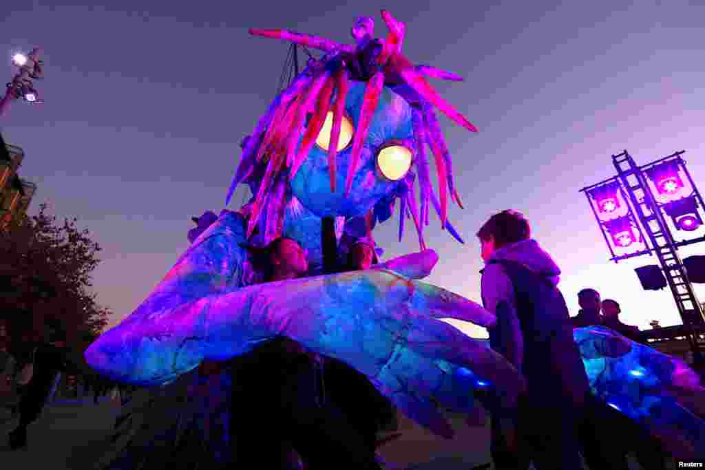 A boy looks at a six-meter tall luminescent puppet, operated by ten performers, during a preview of Vivid Sydney, promoted as the world’s largest festival of light, music and ideas.