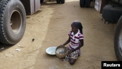 A girl gathers rice spilled from a humanitarian food convoy in the northeastern city of Gao, Mali, June 14, 2012.