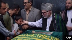 Ten year-old Mustafa, son of Afghan reporter Zabihullah Tamanna,(2L), relatives and friends pray around the coffin during a ceremony at a military hospital in Kabul on June 7, 2016. 