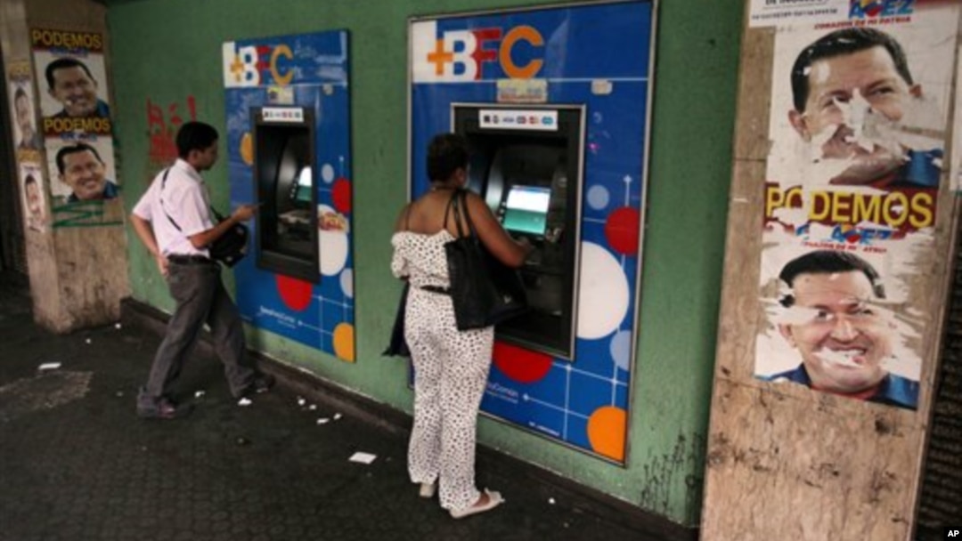 Warga Venezuela menarik uang tunai dari mesin ATM di Caracas, Venezuela (8/2). Pemerintah Venezuela mengumumkan devaluasi (penurunan nilai) mata uang bolivar terhadap dolar menjadi enam koma 30 bolivar untuk satu dolar, yang mulai berlaku hari Rabu pekan mendatang. 