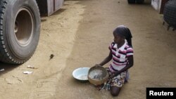 A girl gathers rice spilled from a humanitarian food convoy in the northeastern city of Gao, Mali, June 14, 2012.