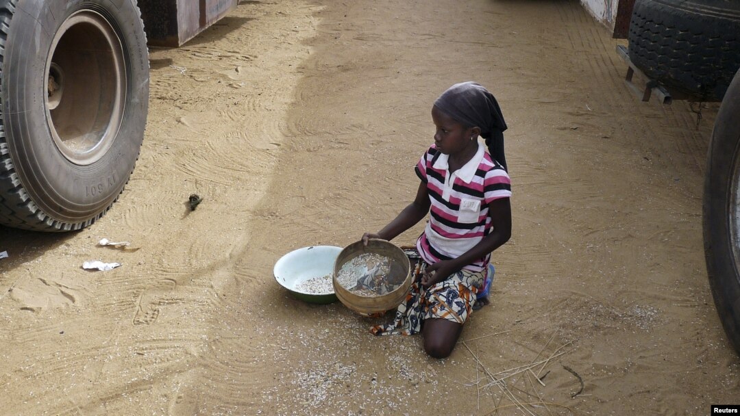 A girl gathers rice spilled from a humanitarian food convoy in the northeastern city of Gao, Mali, June 14, 2012.