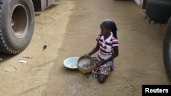 A girl gathers rice spilled from a humanitarian food convoy in the northeastern city of Gao, Mali, June 14, 2012.