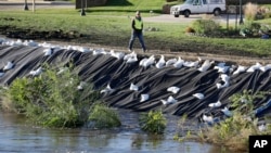 A worker walks across a levee overlooking the flood swollen Cedar River, Tuesday, Sept. 27, 2016, in Cedar Rapids, Iowa. An elaborate system of temporary floodwalls largely protected Cedar Rapids homes and businesses as the river reached its second-highest mark ever.