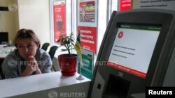 An employee sits next to a payment terminal out of order at a branch of Ukraine's state-owned bank Oschadbank after Ukrainian institutions were hit by a wave of cyber attacks earlier in the day, in Kyiv, June 27, 2017. 