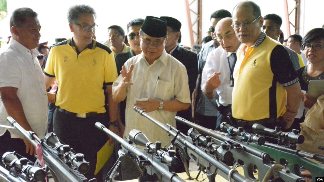 Ketua Fron Pembebasan Islam Moro (MILF), Haji Murad Ebrahim (tengah) menunjukkan kepada Presiden Filipina Benigno Aquino berbagai senjata pemberontak yang diserahkan di kota Sultan Kudarat, Maguindanao, Filipina selatan, Selasa (16/6). 