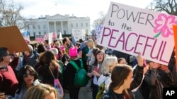 Women's March demonstrators walk past the White House in Washington, Jan. 20, 2018. 