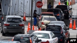 A medical staff member assists people in their cars at a rapid antigen coronavirus testing site at Hard Rock Stadium in Miami Gardens near Miami, Aug. 5, 2020.