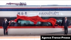 This frame grab from Lao National TV video footage taken Oct. 16, 2021, via AFPTV shows Laos' Minister of Public Works and Transport Viengsavath Siphandone (R) and China's Ambassador to Laos Jiang Zaidong unveiling a sign for a high-speed rail line in Vientiane, Laos.