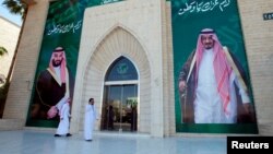 Men walk past murals depicting Saudi Arabia's King Salman bin Abdulaziz Al Saud and Crown Prince Mohammed bin Salman, in Riyadh, Saudi Arabia, Nov. 9, 2017.