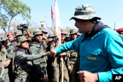 In this handout photo released by Miraflores Press Office, Venezuela's President Nicolas Maduro fist bumps with a cadet at the G/J José Laurencio Silva military training center in the state of Cojedes, Venezuela, May 4, 2019.