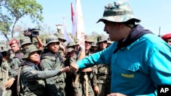 In this handout photo released by Miraflores Press Office, Venezuela's President Nicolas Maduro fist bumps with a cadet at the G/J José Laurencio Silva military training center in the state of Cojedes, Venezuela, May 4, 2019.