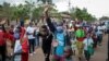 Burundian refugees from Mahama camp in Rwanda wave to gathered media as they arrive back in Gasenyi, Burundi, Aug. 27, 2020.