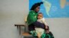 FILE - Habtam Akele carries her daughter as they sit at a school makeshift camp for internally displaced people due to the fighting between the Ethiopian National Defense Force and the Tigray People's Liberation Front forces, in Dessie, Amhara Region, Ethiopia, Oct. 9, 2021.