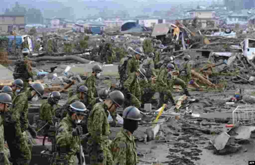 Self-Defense Force members inspects the devastated area before they use heavy machinery in Noda village, northern Japan, Monday, March 14, 2011, three days after a powerful earthquake-triggered tsunami hit the country's east coast. (AP Photo/The Yomiuri S