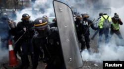 Protesters wearing yellow vests, a symbol of a French drivers' protest against higher fuel prices, clash with riot police on the Champs-Elysee in Paris, Nov. 24, 2018.