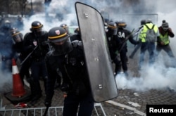 Protesters wearing yellow vests, a symbol of a French drivers' protest against higher fuel prices, clash with riot police on the Champs-Elysee in Paris, Nov. 24, 2018.