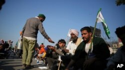 A farmer distributes food to fellow farmers protesting at the border between Delhi and Haryana state, India, Nov. 28, 2020.
