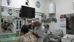 Tailor Yakup, a customer of barber Gul Ali Simsek for forty years, welcomes the reopening but worries of a second lockdown if there are more infections. (D. Jones)