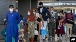 FILE - Families evacuated from Kabul, Afghanistan, walk through the airport to board a bus after they arrived at Washington Dulles International Airport, in Chantilly, Virginia on August 31, 2021. (AP Photo/Gemunu Amarasinghe/File Photo)
