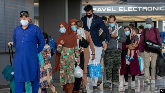FILE - Families evacuated from Kabul, Afghanistan, walk through the airport to board a bus after they arrived at Washington Dulles International Airport, in Chantilly, Virginia on August 31, 2021. (AP Photo/Gemunu Amarasinghe/File Photo)
