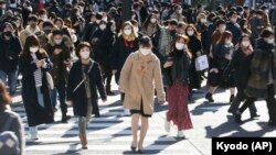  Puluhan orang mengenakan masker untuk mencegah penyebaran virus corona melintasi persimpangan sibuk di distrik perbelanjaan Shibuya Tokyo, Sabtu, 26 Desember 2020. (Foto: Kyodo News via AP)