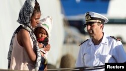 A woman holds a child after disembarking from the Italian Navy ship Borsini in the Sicilian harbour of Palermo, southern Italy, July 20, 2016. 