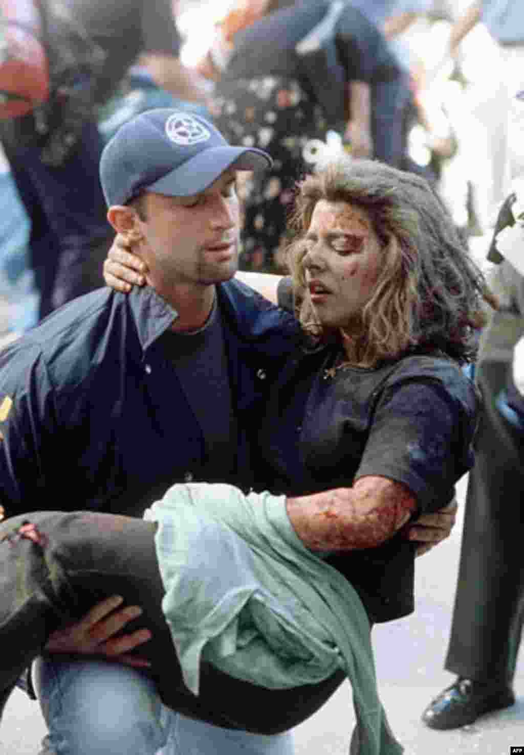 Deputy U.S. marshal Dominic Guadagnoli helps a women after she was injured in the terrorist attack on the World Trade Center in New York, Tuesday, Sept. 11, 2001. (AP Photo/Gulnara Samoilova)