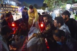 Relawan dan staf medis menurunkan mayat dari truk pickup di luar rumah sakit setelah dua ledakan kuat, yang menewaskan sedikitnya enam orang, di luar bandara di Kabul pada 26 Agustus 2021. (Foto: AFP)