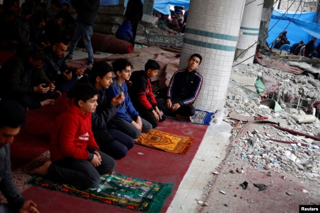 Palestinians perform Friday prayers at the ruins of a mosque destroyed in Israeli strikes in Rafah, southern Gaza Strip, on Feb. 23, 2024.