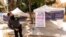 A private security guard gives directions to people looking to get vaccinated, as banners advertise the availability of the Johnson & Johnson and Pfizer COVID-19 vaccines at a county-run vaccination site in Los Angeles on July 22, 2021. 