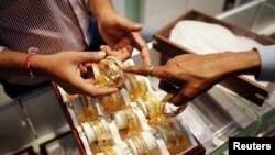 FILE - An employee shows gold bangles to a customer at a jewelry showroom on the occasion of Dhanteras, a Hindu festival associated with Lakshmi, the goddess of wealth, at a market in Mumbai, Nov. 1, 2013. 