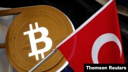 A bitcoin logo is seen next to Turkish flag at a cryptocurrency exchange shop in Istanbul